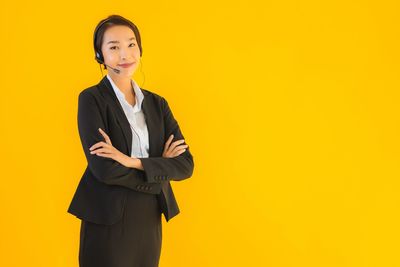 Portrait of a smiling young woman against yellow background