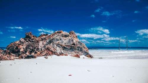 Rock formation at beach against sky