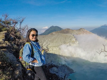 Woman wearing sunglasses standing on mountain against sky