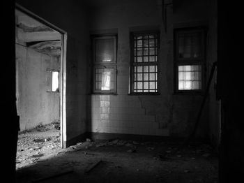 Abandoned messy empty room with fallen wall tiles and dirty windows with bars