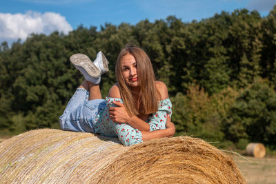 A beautiful young girl is lying on a hay bale