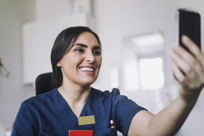 Happy female nurse doing video call through smart phone at hospital