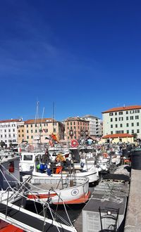 Boats moored in harbor against buildings in city