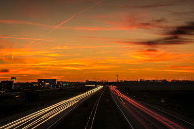 Light trails on highway against sky during sunset