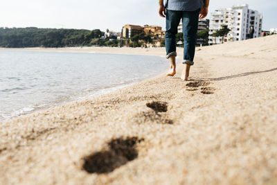 Mature man walking on sand at beach during sunny day