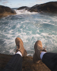 Low section of man sitting by sea