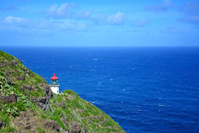 Scenic view of blue ocean with lighthouse against sky