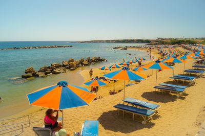 Deck chairs and parasols on beach against clear sky