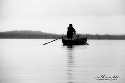 Silhouette boat in calm lake against sky