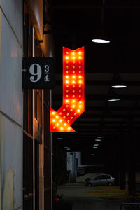 Illuminated road sign on street at night