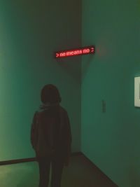 Rear view of man standing against illuminated wall