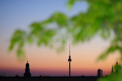 Illuminated fernsehturm against sky during sunset