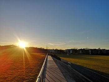 Railroad tracks on field against sky during sunset