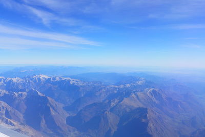 Aerial view of snowcapped mountains against blue sky