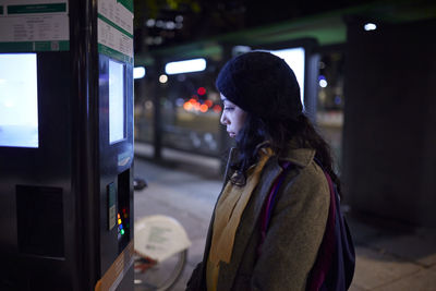 Side view of woman standing in city during winter