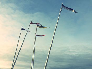 Low angle view of flags against cloudy sky