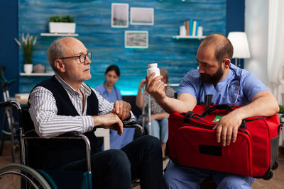 Doctor showing medicine to senior man at rehab