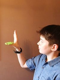 Close-up of boy playing with fidget spinner against wall