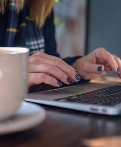 Midsection of woman using laptop at table