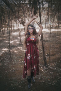 Full length portrait of woman standing in forest
