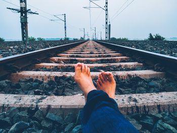 Low section of man on railroad track against sky