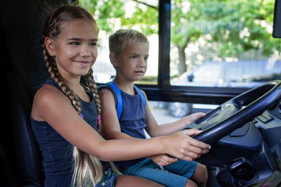 Kids pretending to drive a bus, sitting in the driver's cabin with smiles and curiosity