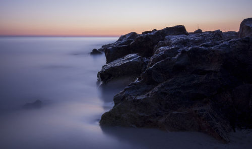 Scenic view of sea and rock formation at sunset