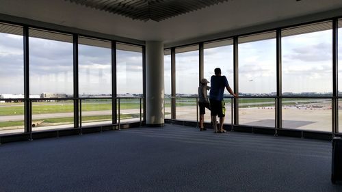 Rear view of people standing on glass window