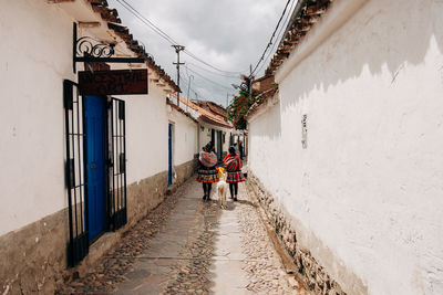 Rear view of people walking on footpath amidst buildings