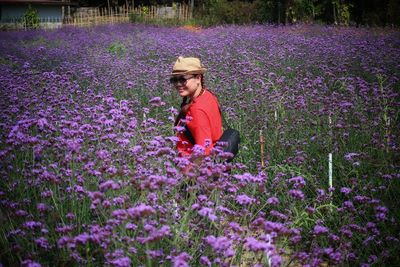 Woman standing on purple flowering plants on field