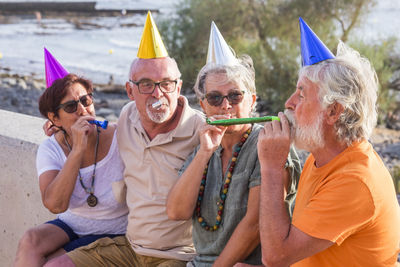 Friends looking at man blowing party horn blower