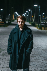 Portrait of man standing on footpath at night