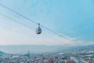 Low angle view of overhead cable cars against sky