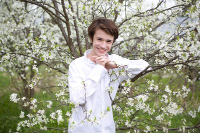 Portrait of smiling young man standing against tree