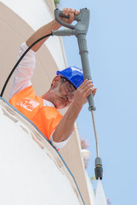 Low angle view of man working against sky