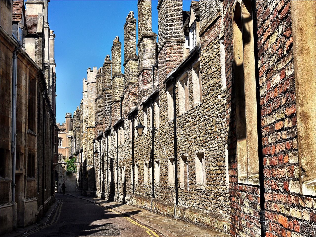 architecture, built structure, building exterior, the way forward, wall - building feature, building, street, brick wall, graffiti, old, day, diminishing perspective, low angle view, outdoors, clear sky, sunlight, house, no people, residential building, wall