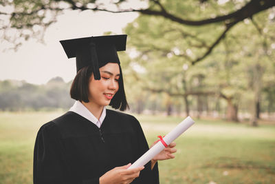 Young woman in graduation gown holding certificate