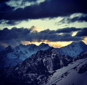 Scenic view of snow covered mountains against cloudy sky