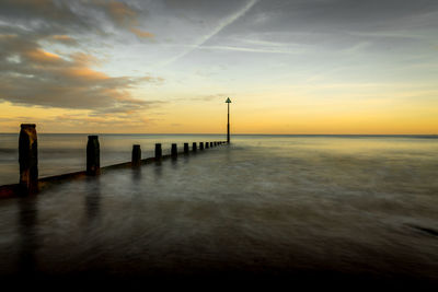 Pier on sea against sky during sunset