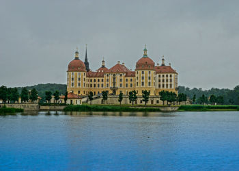 View of building by lake against sky