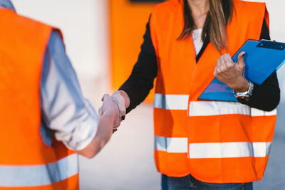 Midsection of architect shaking hands with colleague