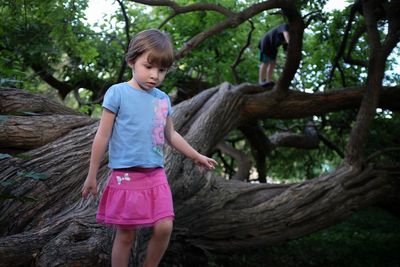 View of girl playing on tree trunk