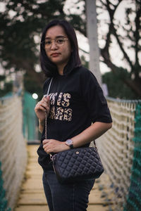 Portrait of young woman standing against trees