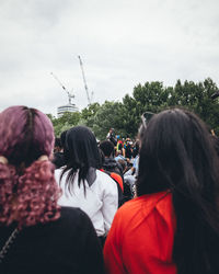 Rear view of people looking at trees against sky