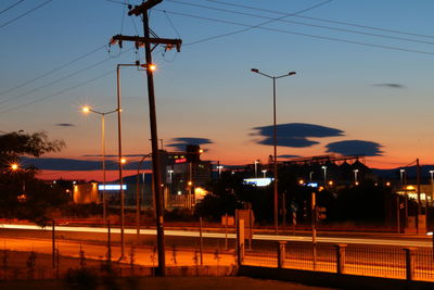 Illuminated street light over road during sunset