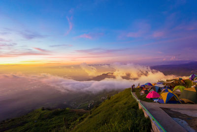 People on land against sky during sunset