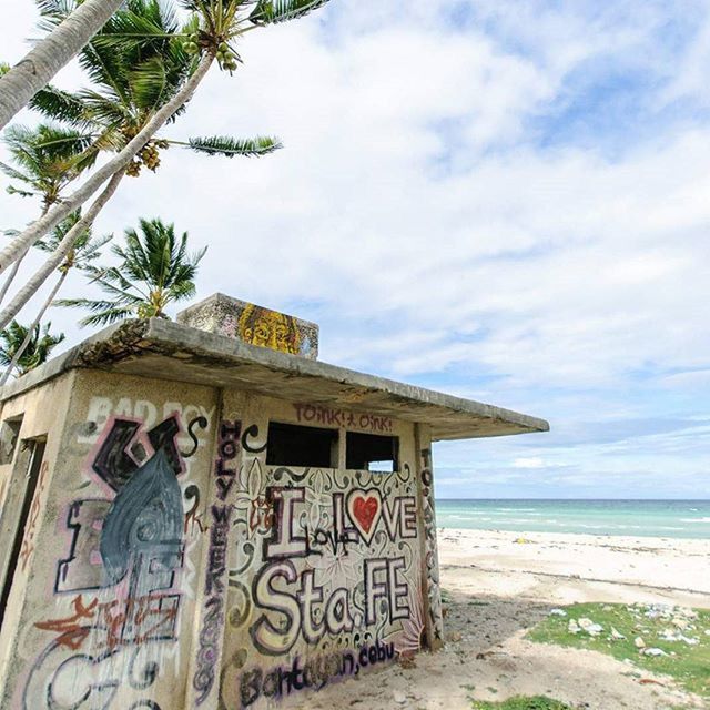 sea, sky, water, beach, horizon over water, built structure, tree, cloud - sky, palm tree, shore, architecture, cloud, nature, sand, tranquility, day, text, tranquil scene, building exterior, outdoors