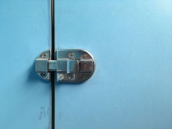 Close-up of metallic latch on blue door