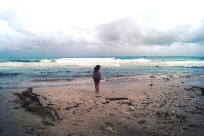 Rear view of woman on beach against sky