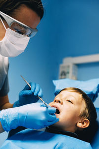 Dentist operating cheerful boy in medical clinic